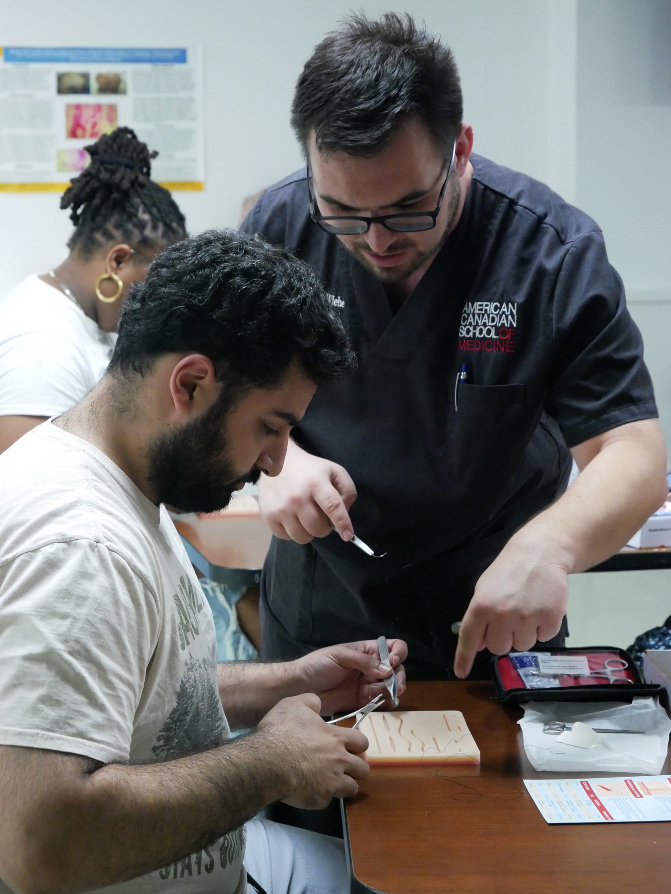 ACSOM faculty member guiding a student during a hands-on classroom exercise